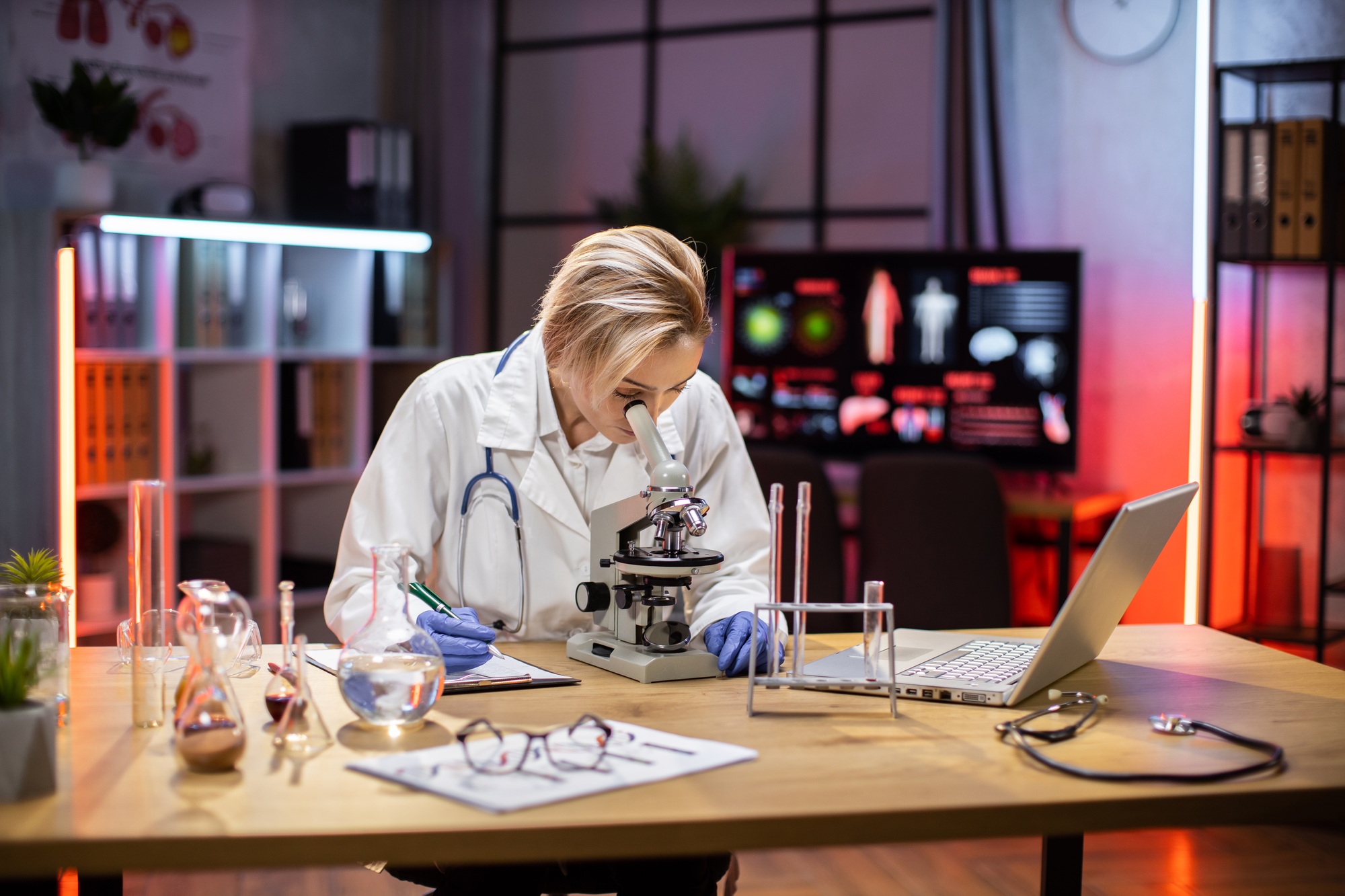 Young female researcher looking at the microscope in the life science.