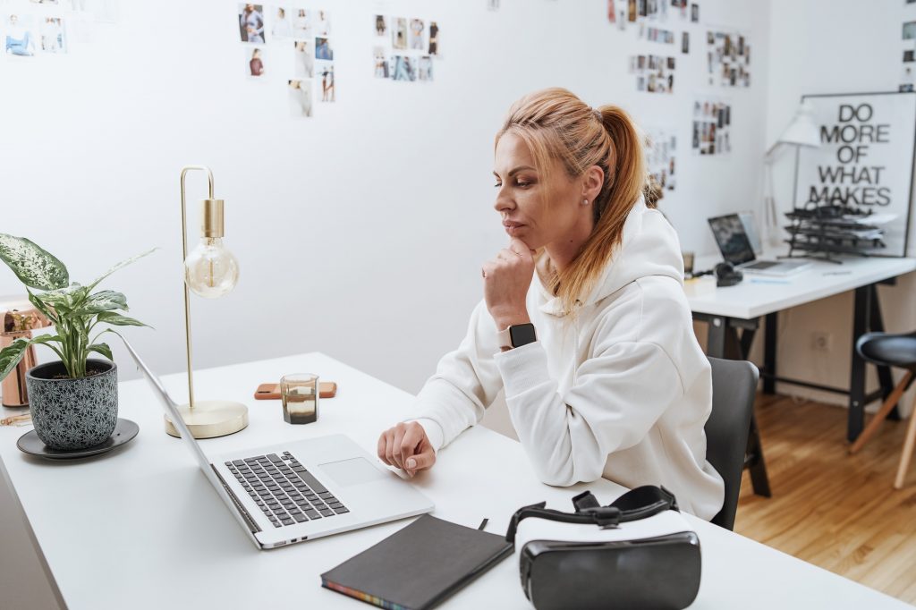 Beautiful female businessperson types on laptop sitting at table